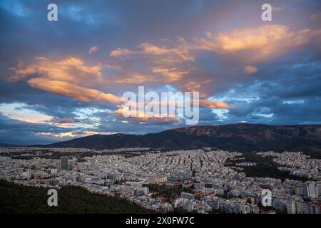 Majestätischer Sonnenuntergang mit herrlichen Wolken über dem Hymettus-Berg und der Stadt Athen, Griechenland. Es gibt mehrere Stadtteile wie Zografou und Papagou. Stockfoto