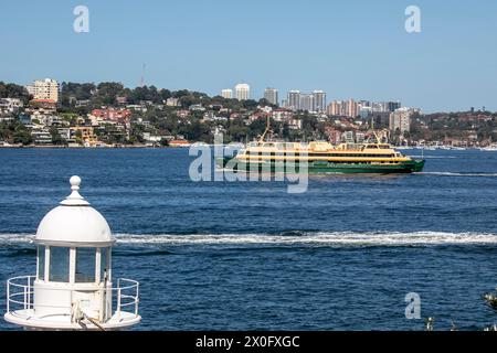 Sydney Harbour, die Manly Ferry fährt zwischen Manly Beach und Circular Quay, Blick auf den Leuchtturm Bradleys Head und in die fernen östlichen Vororte Stockfoto