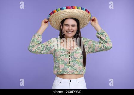 Junge Frau mit mexikanischem Sombrero-Hut auf violettem Hintergrund Stockfoto