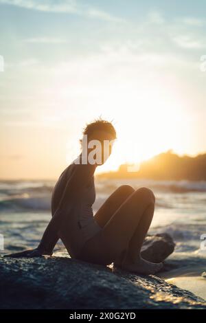 Frau auf dem Meer, die den Sonnenuntergang beobachtet. Stockfoto