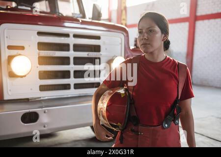 Porträt einer Feuerwehrfrau, die wegschaut und auf der Feuerwache steht Stockfoto