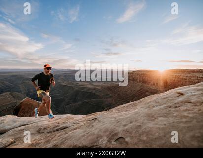 Ein männlicher Trailläufer joggt am mesa Edge in der Wüste Utah, Sonnenuntergang. Stockfoto