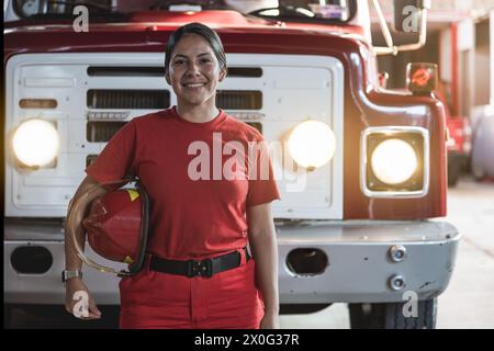 Porträt einer lächelnden Feuerwehrfrau, die auf der Feuerwache steht Stockfoto