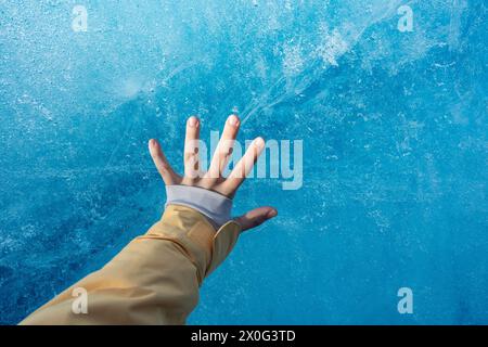 Mädchenhand berührt Cold Blue Ice berg im isländischen Wintergletscher Stockfoto