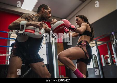 Starke Boxerin, die Muai Thai im Fitnessstudio spielt Stockfoto