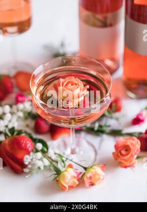 Nahaufnahme einer rosafarbenen Mini-Rose, die in einem Coupé-Glas Rosenwein schwimmt, Stockfoto