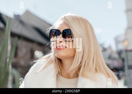 Reife Frau mit blonden Haaren, die Sonnenbrille an einem sonnigen Tag trägt Stockfoto