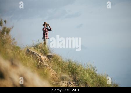 Frau mit Hut und kariertem Outfit, die die Wüste beobachtet. Stockfoto