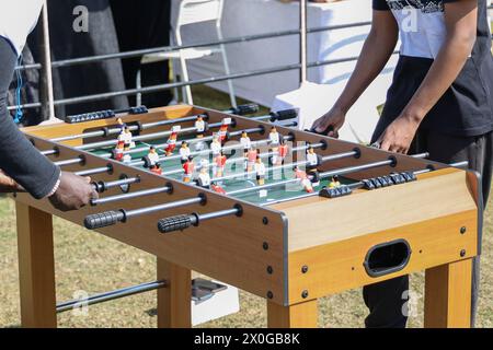 Zugeschnittenes Bild eines Jungen und eines jungen Mannes, die Tischkicker spielen, während sie sich im Freien entspannen Stockfoto