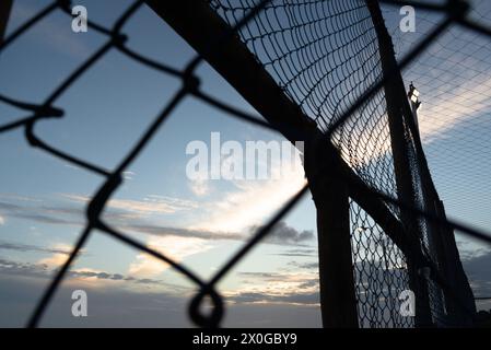 Netz und Zaun eines alten verlassenen Sportplatzes gegen Sonnenuntergang. Sportausrüstung. Stockfoto
