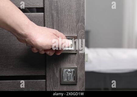 Mann, der die Holztür im Haus öffnet, Nahaufnahme der Hand am Griff Stockfoto