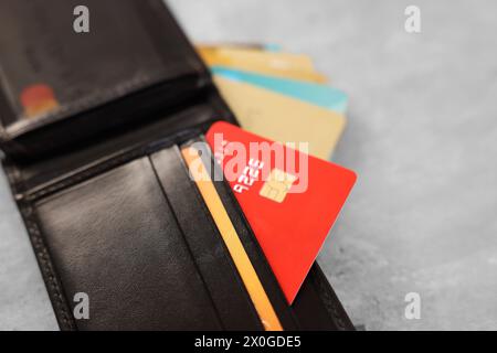 Viele verschiedene Kreditkarten und Ledergeldbörse auf grauem Tisch, Nahaufnahme Stockfoto