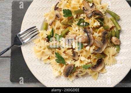 Vegetarische Pasta mit Pilzen, Petersilie, Bohnen und Käse auf grauem Holztisch, Blick von oben Stockfoto