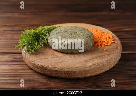 Vegetarisches Produkt. Rohe Linsenkotelett und Zutaten auf Holztisch Stockfoto