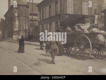 Ein offener Einpferdewagen mit Haushaltswaren wird von einem deutschen Soldaten mit einer Pickelhaube begleitet. Frauen laufen auf ihm und neben ihm wird der Wagen von einem alten Mann gefahren. Rechts von der Straße befinden sich unzerstörte Steinhäuser. Abgesehen von diesen Leuten ist niemand auf der Straße. Die Franzosen fliehen vor den Kämpfen in und um ihre Stadt [automatisierte Übersetzung] Stockfoto