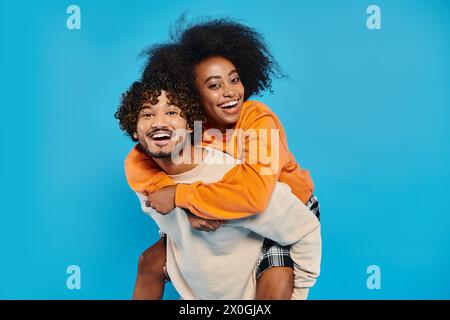 Ein interrassisches Paar Studenten in lässiger Kleidung stehen zusammen, und der Mann unterstützt die Frau auf dem Rücken. Stockfoto