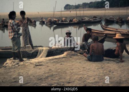 Eine Gruppe von Fischern sitzt neben ihren Booten am Ufer des Irrawaddy in Bagan und bereitet ihre Netze für den kommenden Fischfang vor. [Automatisierte Übersetzung] Stockfoto