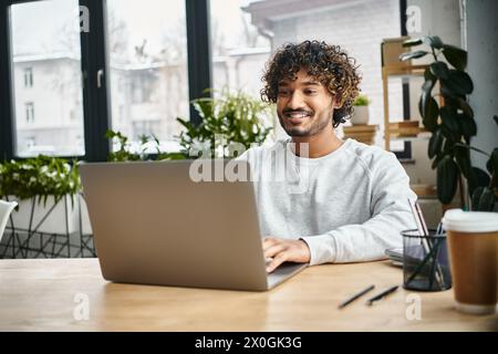 Ein Mann mit unterschiedlichem Hintergrund sitzt in einem modernen Coworking-Raum vor einem Laptop und beschäftigt sich mit der digitalen Arbeit. Stockfoto