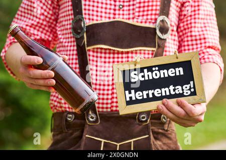 12. April 2024: Ein großer Gruß zum Herrn-Tag auf einem Brett, das von einem Mann in Lederhosen gehalten wird, zusammen mit einer Flasche Bier. Gruß zum Männentag. FOTOMONTAGE *** schöner Herrentag Gruß auf einer Tafel die ein Mann in Lederhose zusammen mit einer Flasche Bier halten. Herrentagsgruß. FOTOMONTAGE Stockfoto