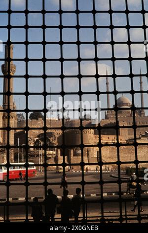 Blick durch ein Ostfenster des Sultan-Mausoleumses der Sultan-Hassan-Moschee zu einem Minarett der Mohammed-Ali-Moschee und der Zitadelle von Saladin im Hintergrund. [Automatisierte Übersetzung] Stockfoto