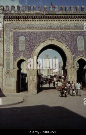 Ein Mann reitet auf einem Esel vorbei an Passanten vor dem Tor Bab Bou Jeloud in der Medina (Altstadt) von Fez. [Automatisierte Übersetzung] Stockfoto