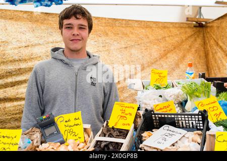 Junge Erwachsene, Teenager, der Lebensmittel vom Marktstand seines Vaters auf dem lokalen Wochenmarkt am Blaak Square verkauft. Rotterdam, Niederlande. MRYES Rotterdam Blaak, dinsdagmarkt Zuid-Holland Nederland Copyright: XGuidoxKoppesxPhotox Stockfoto