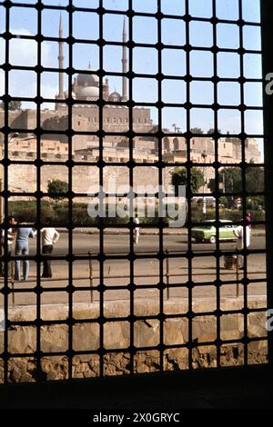 Blick durch ein Ostfenster des Sultan-Mausoleumses der Sultan-Hassan-Moschee zur Zitadelle von Saladin mit der Mohammed-Ali-Moschee in Kairo. [Automatisierte Übersetzung] Stockfoto