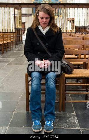 Frau, die Breda in den Niederlanden denkt und betet. Eine halbadulte kaukasierin, die in einer protestantischen Kirche nachdenkt und betet. Breda Down Town Noord-Brabant Nederland Copyright: XGuidoxKoppesxPhotox Stockfoto