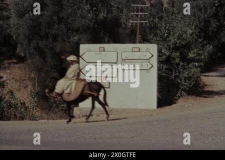 Ein Mann reitet auf einem Esel an einem Richtungsschild in Moulay Idriss vorbei. [Automatisierte Übersetzung] Stockfoto