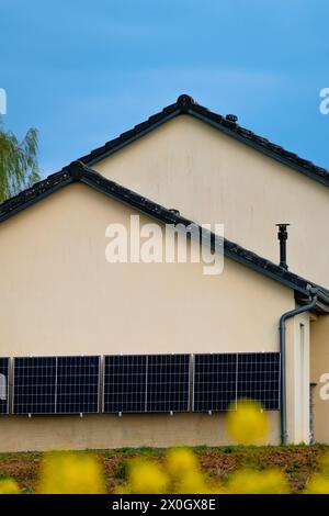 Solarpaneele an einer gut belichteten Wand eines einzelnen Hauses, Einsparungen nach der Energiekrise, Öko-Bürgergeste, grüne Energie Stockfoto