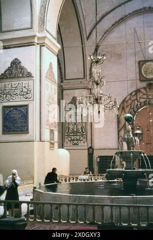 Muslimische Frauen mit Kopftuch an einem Brunnen in der großen Moschee Ulu Cami in Bursa. [Automatisierte Übersetzung] Stockfoto
