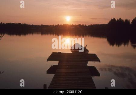 Ein Ruderboot in der Mitternachtssonne auf einem finnischen See. Stockfoto