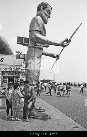 Menschen gehen durch eine riesige Statue auf der Promenade am Strand von Coney Island in New York. Stockfoto