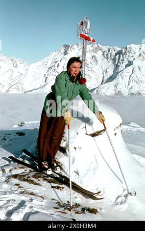 Frau mit Skiern auf einem Gipfel vor einem Bergpanorama. Stockfoto