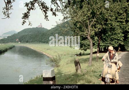 Ein Mann mit einem Lambretta-Roller, der am Straßenrand unter einem Fluss steht Stockfoto