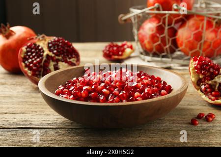 Reife saftige Granatapfelkörner in der Schüssel auf Holztisch Stockfoto