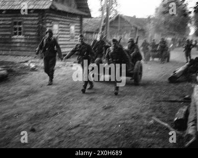 In einem Dorf im Hinterland der Ostfront ziehen deutsche Soldaten Infanteriewaffen entlang der staubigen Straße. Das Foto wurde wahrscheinlich im Zusammenhang mit Partisanenkämpfen aufgenommen. Das Bild wurde von einem Mitglied des Radfahrgrenadierregiments 2 aufgenommen, vermutlich im mittleren Abschnitt der Ostfront. [Automatisierte Übersetzung] Stockfoto