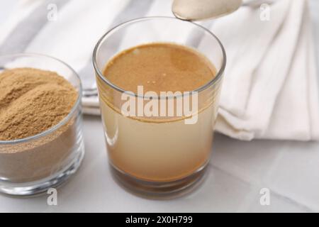 Lösliche Faser mit Wasser in Glas und Pulver auf weißem Tisch, Nahaufnahme Stockfoto