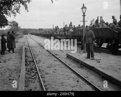 Russische Kriegsgefangene sitzen in offenen Güterwagen. Einheimische beobachten den Tatort, ein deutscher Soldat steht auf dem Bahnsteig mit einer Signalfahne. Das Bild wurde von einem Mitglied des Radfahrgrenadierregiments 2/Radfahrsicherungsregiment 2 an der Ostfront aufgenommen. [Automatisierte Übersetzung] Stockfoto