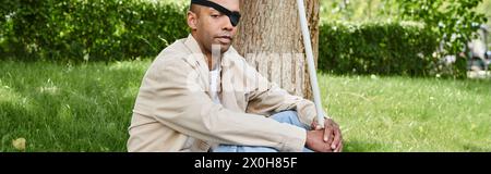 Ein Afroamerikaner mit Myasthenia gravis-Syndrom sitzt neben einem Baum Stockfoto