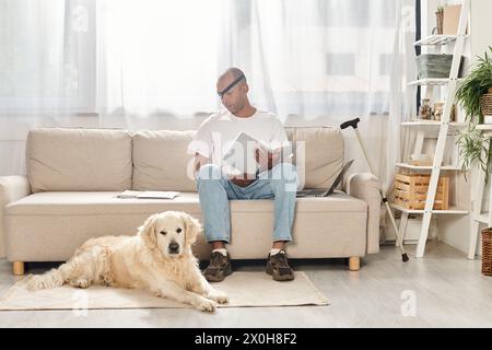 Ein behinderter Afroamerikaner mit Myasthenia gravis-Syndrom entspannt sich auf einer Couch neben seinem treuen Labrador-Hund. Stockfoto