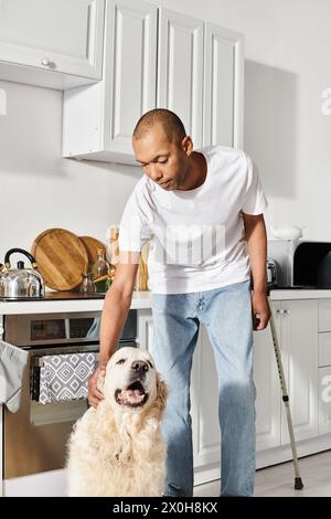 Ein Afroamerikaner mit Myasthenia gravis kuschelt friedlich seinen Labrador-Hund in einer gemütlichen Küche. Stockfoto