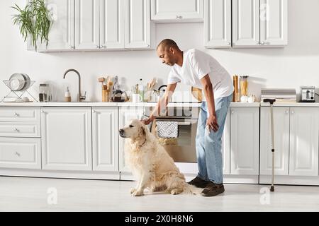 Ein behinderter Afroamerikaner mit Myasthenia gravis streichelt seinen Labrador-Hund in einer warmen Küche. Stockfoto