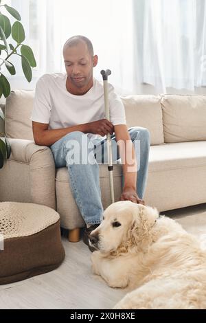 Ein Afroamerikaner mit Myasthenia gravis sitzt bequem auf einer Couch neben seinem treuen Labrador-Hund. Stockfoto