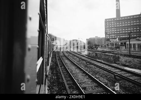 Eine S-Bahn nähert sich dem Bahnhof Alexanderplatz an der Stadtbahnlinie. Sie sehen bereits die Bahnhofshalle hinten und die Hauptgleise rechts, das linke noch mit einer Bahnschiene, und das Gelände des Kleingutbahnhofs am Stadbahnbögen. [Automatisierte Übersetzung] Stockfoto