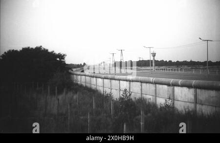 Hier sehen Sie mehrere Generationen der immer perfekteren Mauer rund um West-Berlin. Im Vordergrund links befindet sich der Stacheldrahtzaun, dahinter die komplette Barriere mit Mauer, Todesstreifen und Außenmauer und Wachturm sowie die Beleuchtung. Im Hintergrund sehen Sie die Neubauten, wahrscheinlich im Bereich des Tirschenreuter Rings - West-Berlin wieder. [Automatisierte Übersetzung] Stockfoto