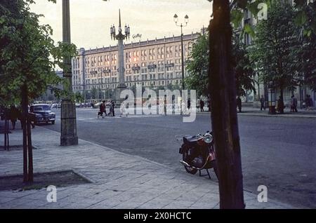 Die Abendsonne spiegelt sich in den Fenstern eines typischen sozialistischen Nachkriegsgebäudes auf dem Platz der Verfassung in der Mitte von Ulica Marszalkowska. Davor eine riesige Straßenlaterne. Die Leute überqueren die Straße. [Automatisierte Übersetzung] Stockfoto