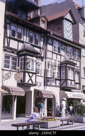 Blick auf das Wohn- und Geschäftshaus an der Maximilianstraße 6. Eine Frau sitzt auf einer Bank, Passanten sind unterwegs. [Automatisierte Übersetzung] Stockfoto