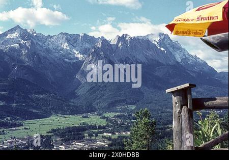 Panorama vom Bergrestaurant St. Martin am Grasberg am Fuße des Kramer. Ein gelber und roter Sonnenschirm davor. [Automatisierte Übersetzung] Stockfoto