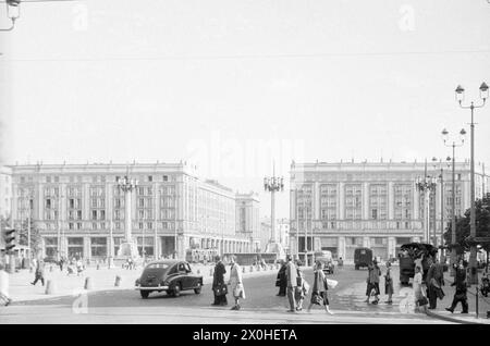 Fußgänger überqueren eine breite Straße, die von wenigen Autos und kleinen Lkws genutzt wird. [Automatisierte Übersetzung] Stockfoto